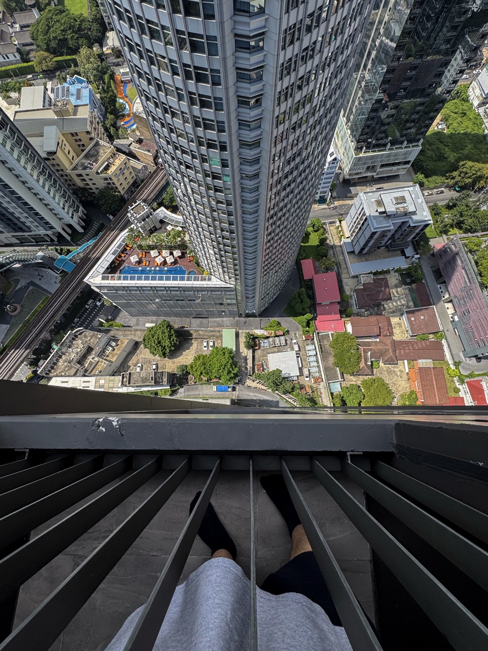 Bangkok, Thailand - November 11, 2024: Tourist high up in a skyscraper, looking down from the big window and capturing the luxurious skyline view on a bustling Thai metropolis.